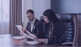Two professionals reviewing deal documents in a boardroom
